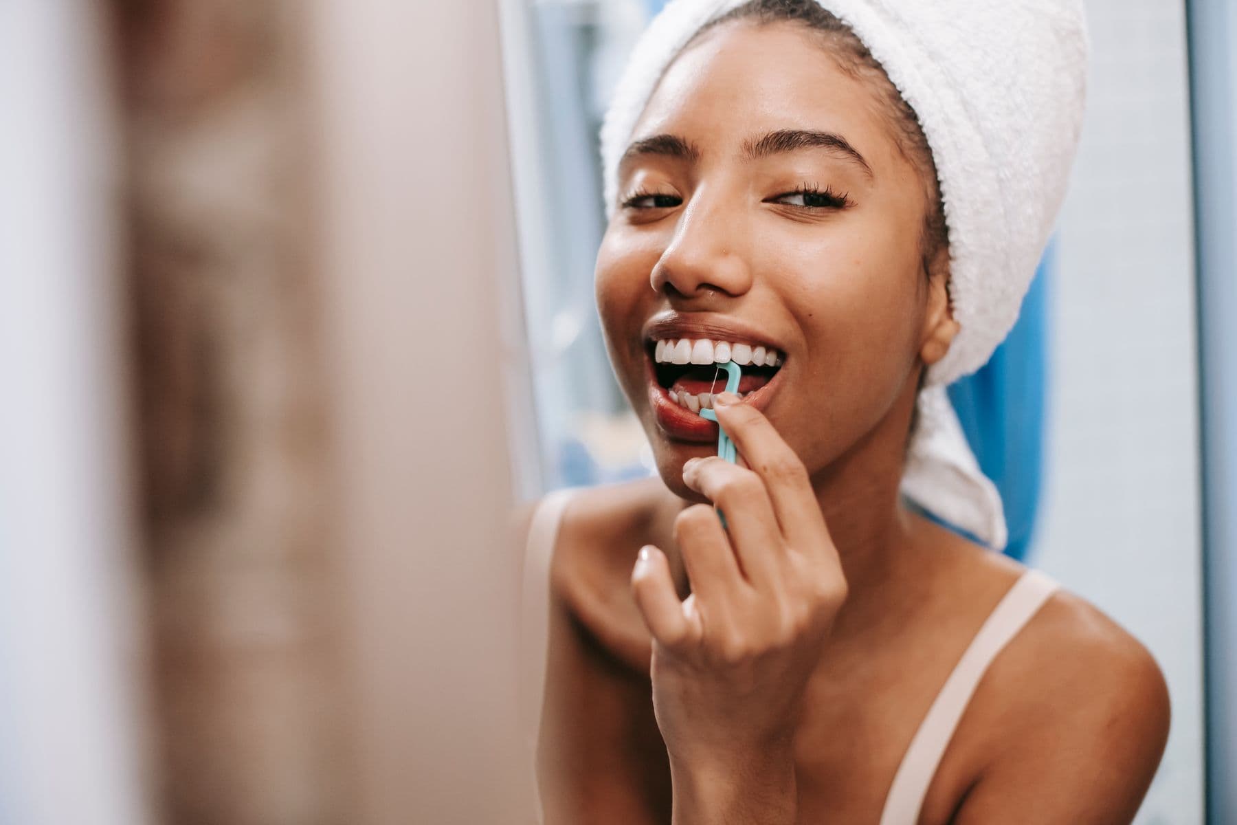 A woman cleaning between her teeth with a floss pick