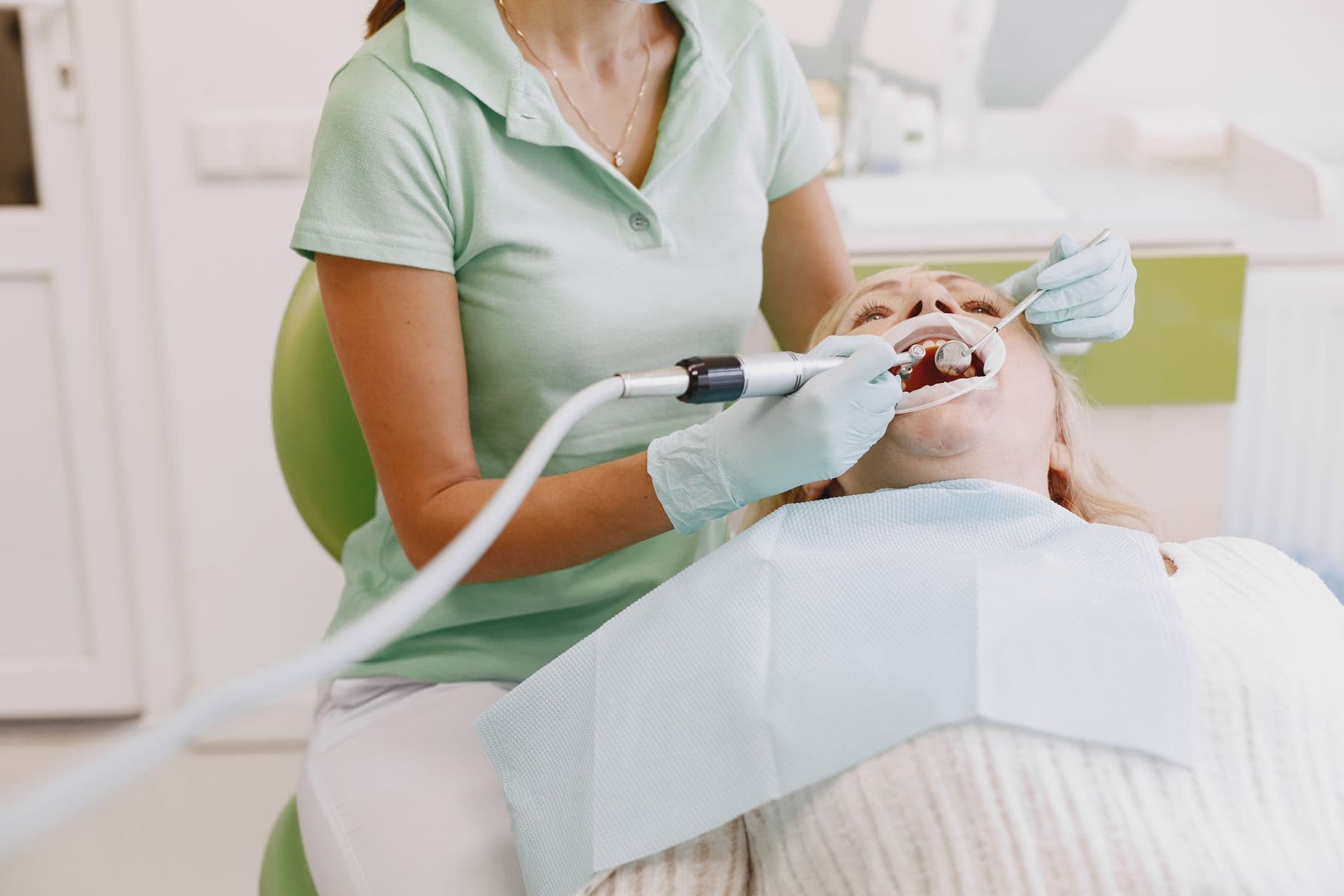 Tandhygienist rengör en patients tänder