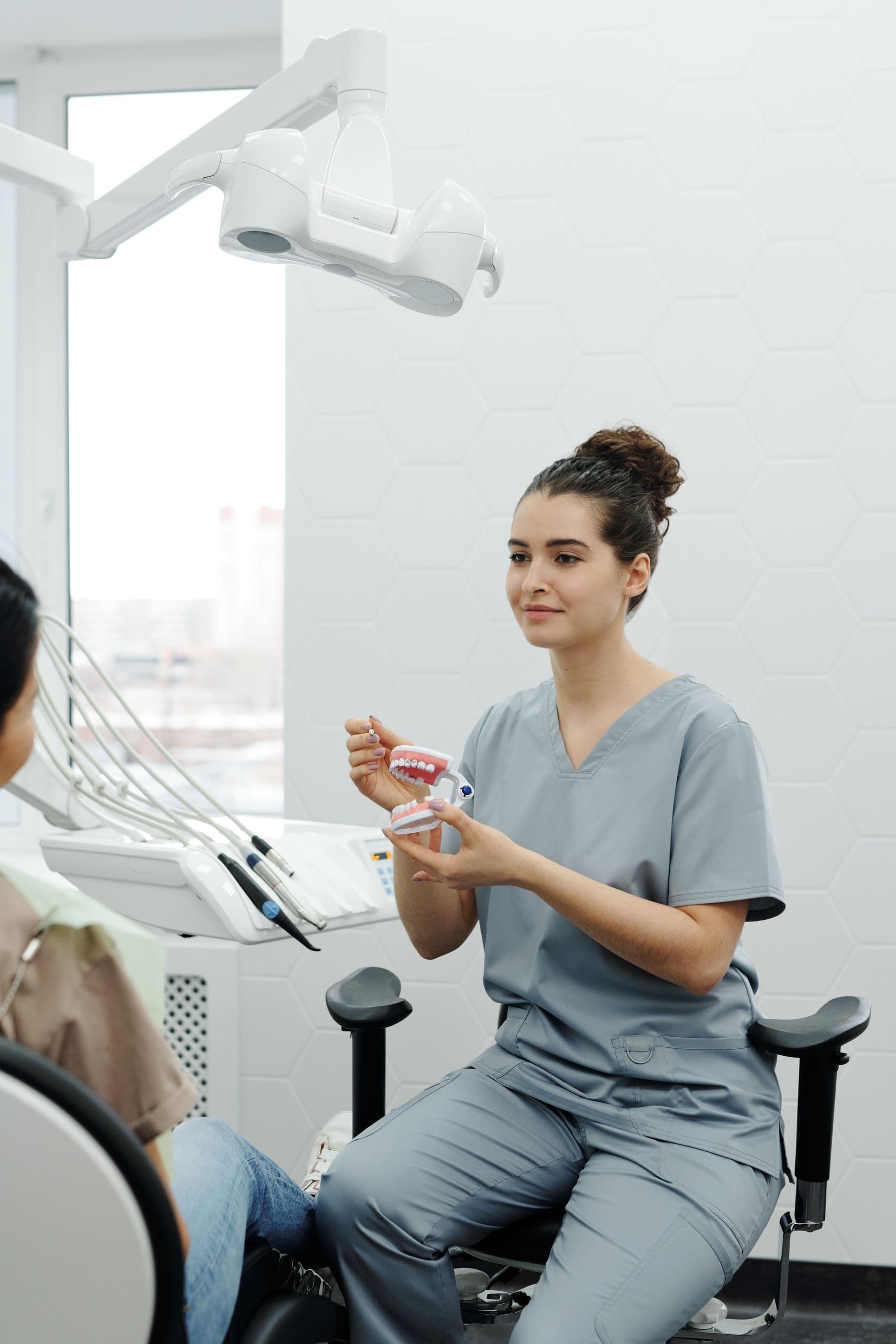 A dental hygienist explaining with a tooth model