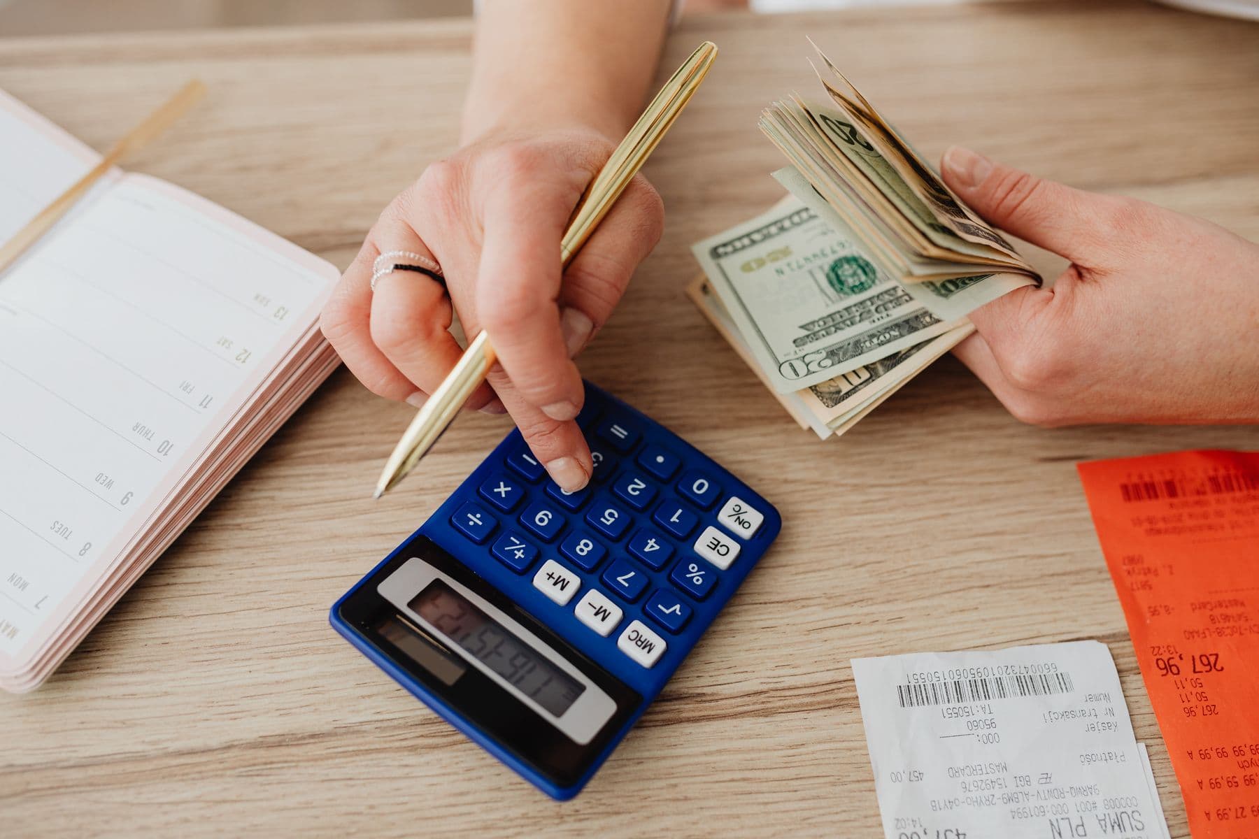 A hand counting money with a calculator