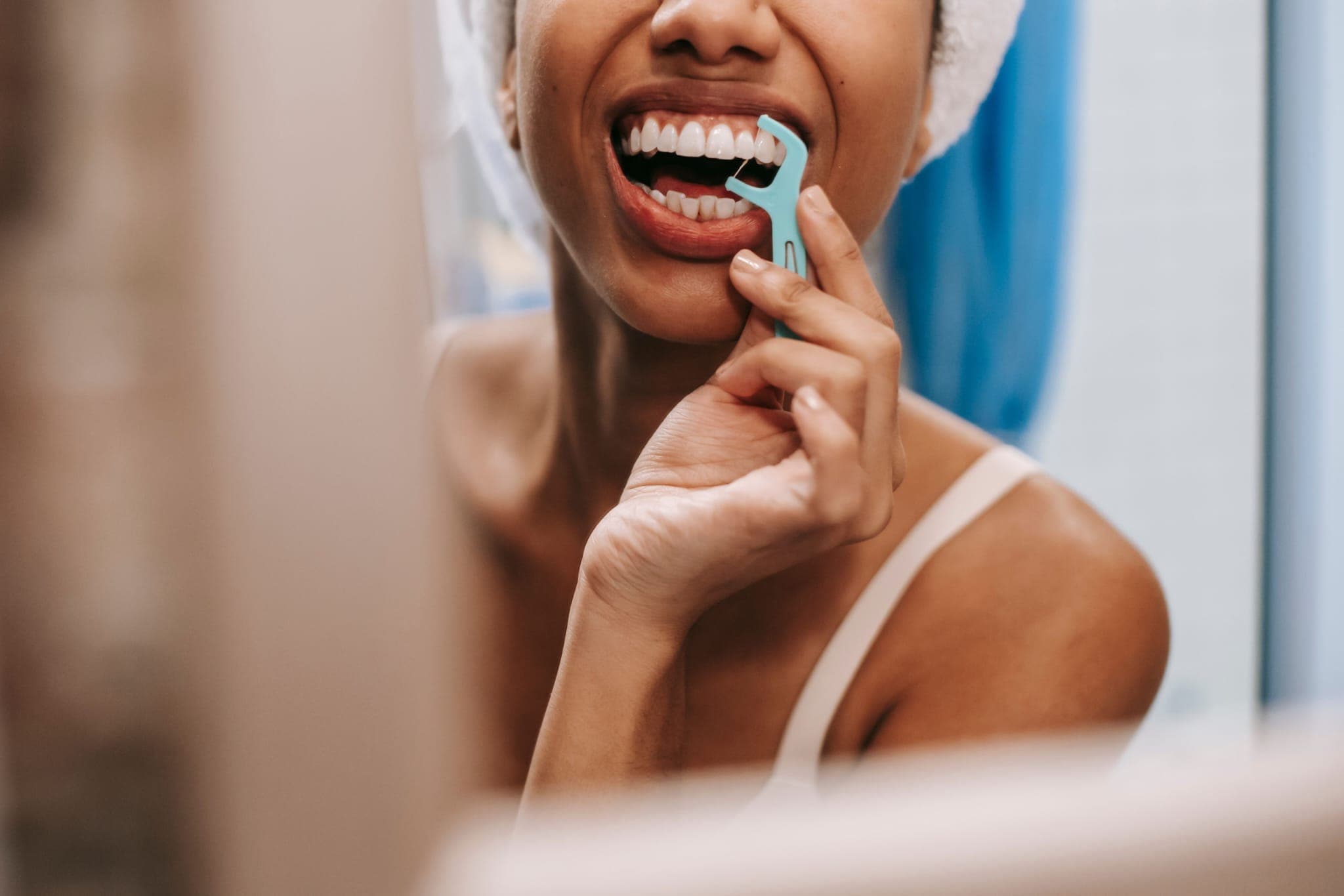 A woman cleaning between her teeth with a floss pick